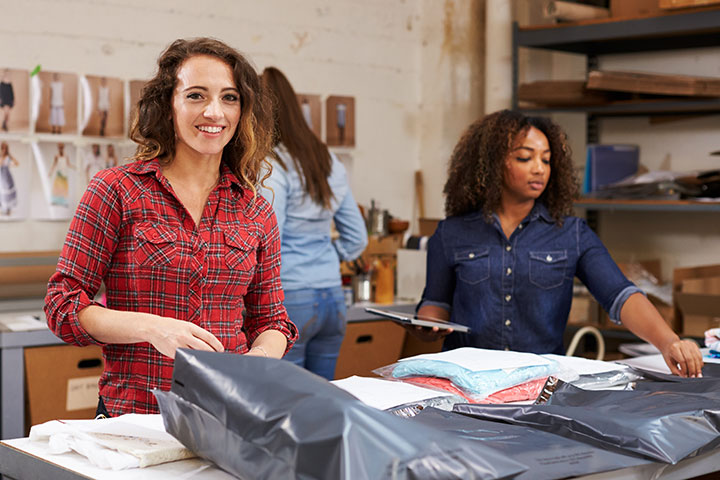 Team packing orders for distribution, woman smiles to camera